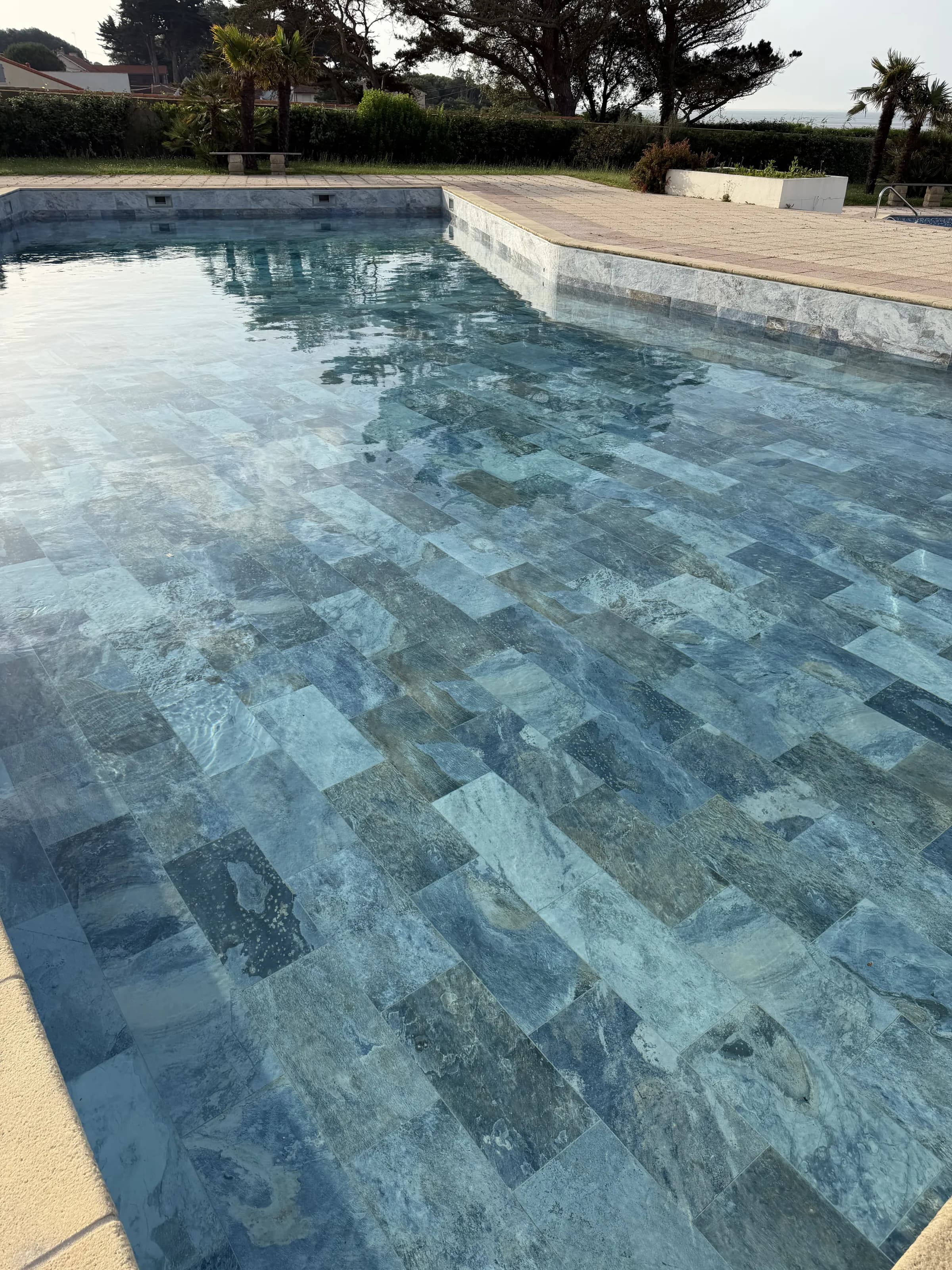 Après rénovation : bassin collectif de Pornic en carrelage effet pierre de Bali, eau claire.