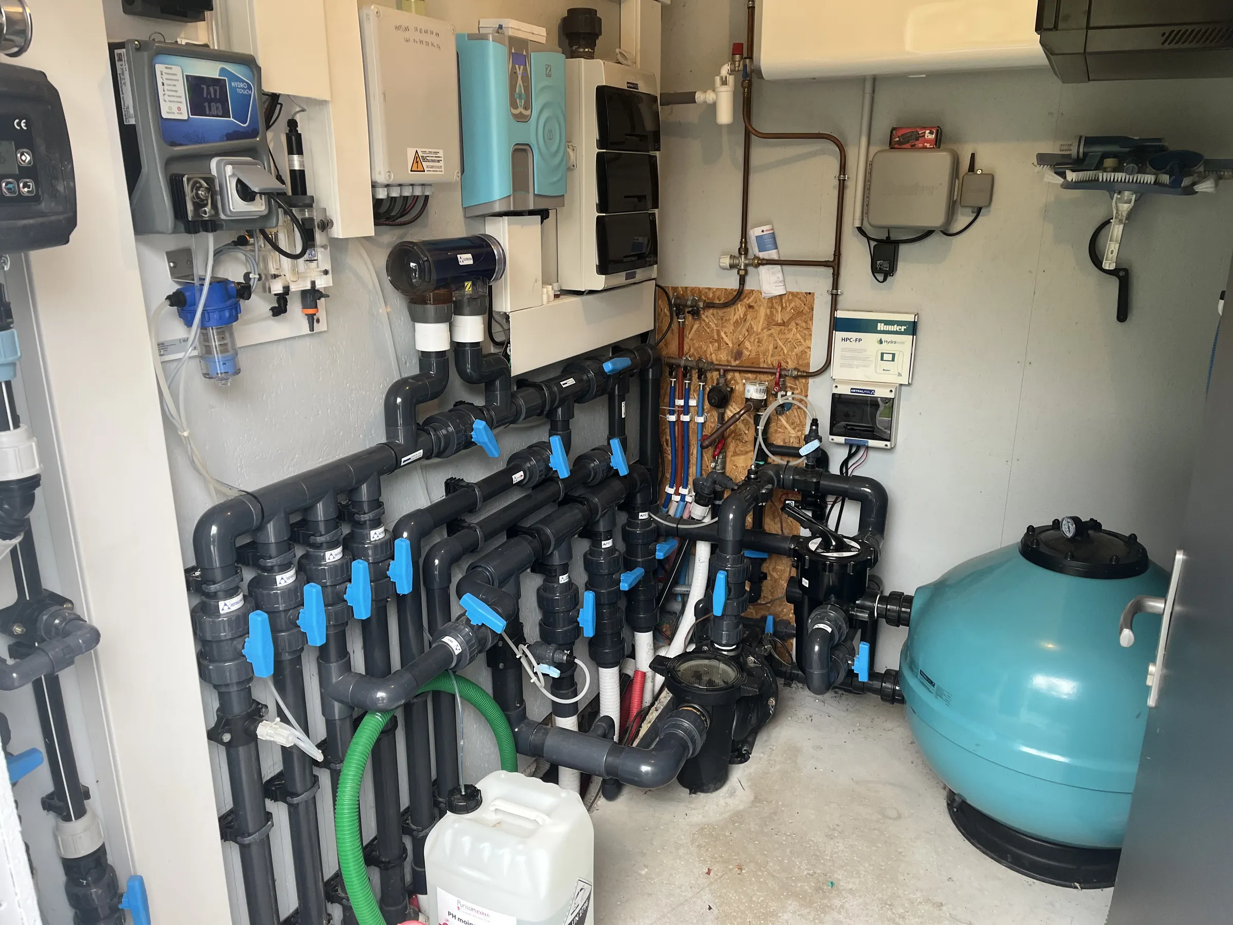 Local technique créé pour une piscine à débordement : filtre à sable, pompe, nourrices et vannes, électrolyseur, régulation pH et coffret électrique.